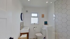 A small, modern bathroom with a toilet, sink, and a small window. - D46 Wrangarrie, Riviere Towans (Hayle)