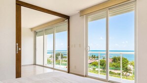A bedroom with a large bed, sliding glass doors leading to a balcony with a view of the ocean. - Beachfront 3BR - Ocean View - 70m Pool - Cancun (Cancún)
