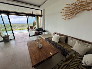 A modern living room with a large window, a wooden coffee table, a sofa, and a piano.
