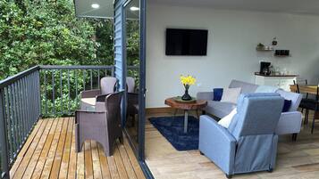 A balcony with wicker furniture, a grey sofa, and a small table with a vase of flowers.