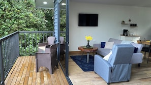 A balcony with wicker furniture, a grey sofa, and a small table with a vase of flowers.