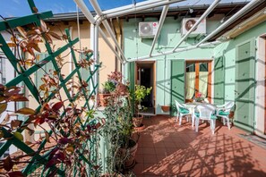 A patio with a table and chairs, surrounded by potted plants and a green trellis. - Red Mansarda - Italia (Viareggio)