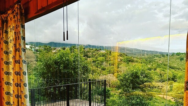 Ein Zimmer mit Balkon und Blick auf eine üppige grüne Landschaft.