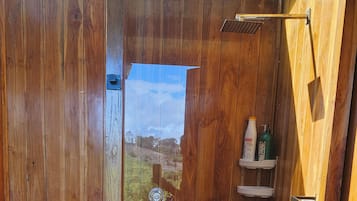 Un baño rústico con inodoro, ducha y ventana.