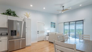 A modern kitchen with stainless steel appliances, a dining area with a wooden table and chairs, and a large window offering a scenic view. - 180° Table Rock Lake View | 2-Min to SDC | Kayaks (Branson)