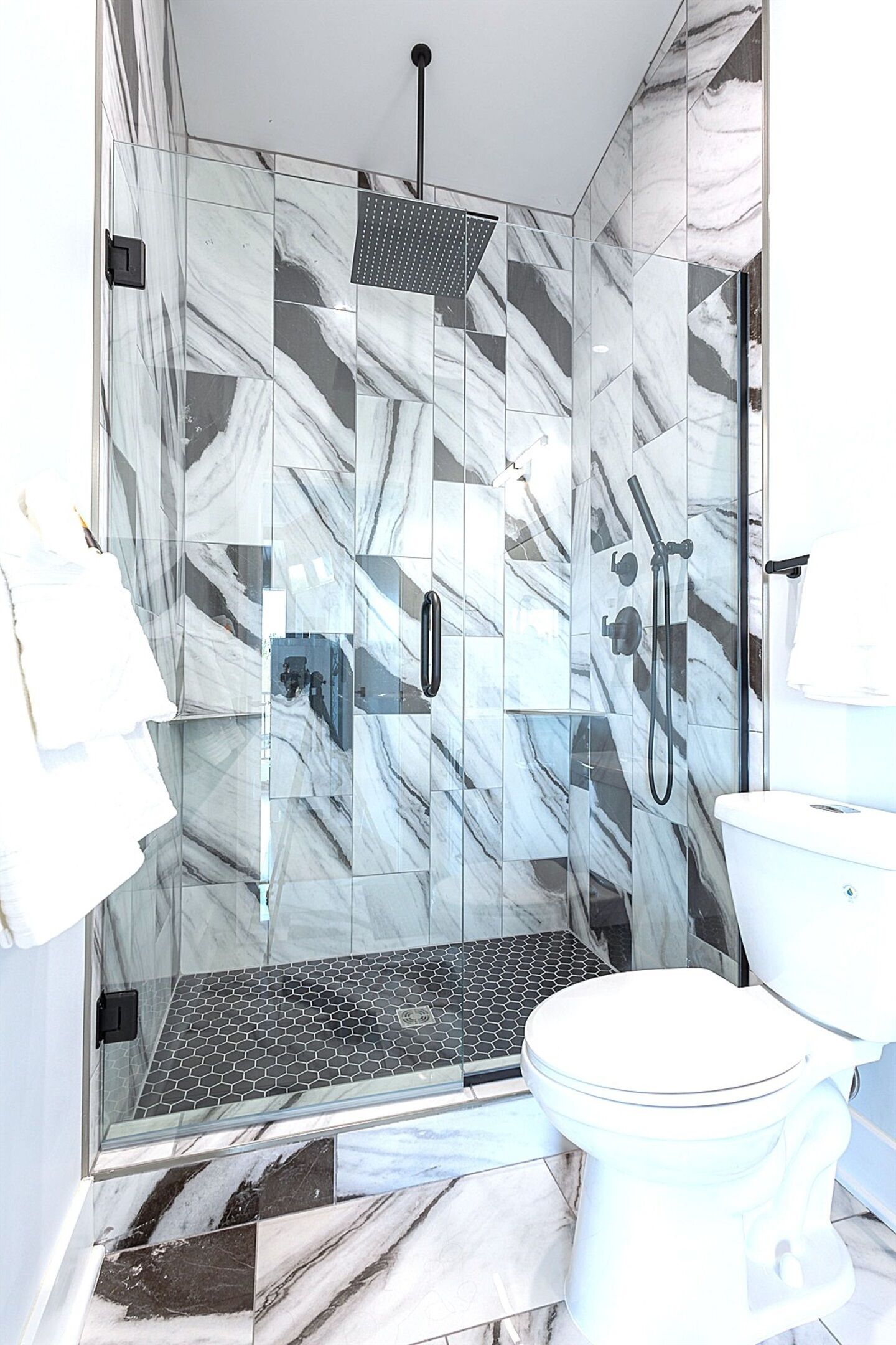 A modern bathroom with a glass-enclosed shower, a toilet, and a sink.