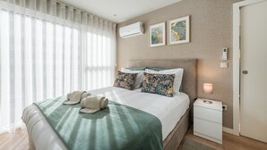 A modern hotel room with a large bed, a bedside table with a lamp, and a wall-mounted air conditioner. - GuestReady - A dream stay in Porto (Porto)