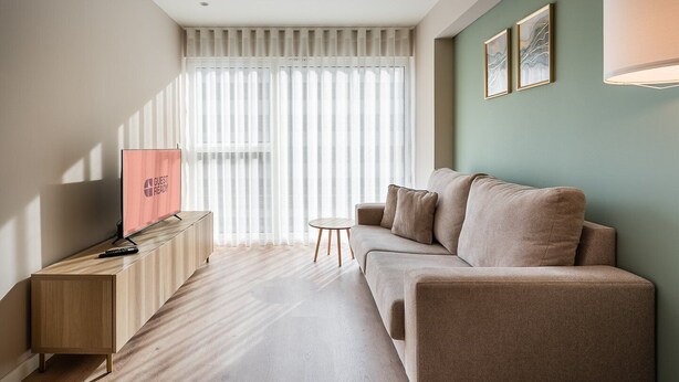 A modern living room with a sofa, a small table, and a TV on a wooden cabinet. - GuestReady - A dream stay in Porto (Porto)