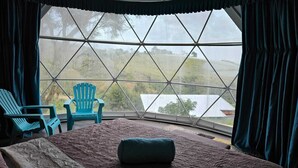 A room with a large window, a bed, two chairs, and a view of the outdoors. - Mountain view dome, pet friendly, trails and near Poas Volcano. (Carrizal)