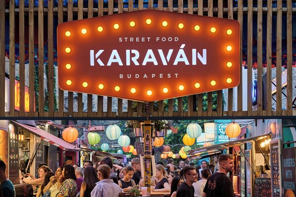 A busy street food market with a prominent sign for 'KARAVÁN BUDAPEST'.