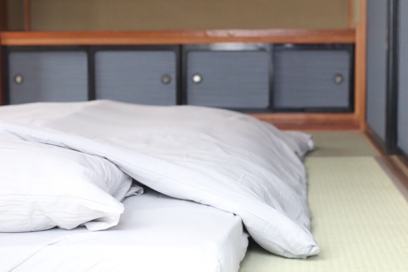 A bed with a white mattress and pillows, a wooden headboard, and a green floor.