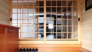 A traditional Japanese-style room with sliding doors, a wooden bench with shoes, and a tiled floor. - decopinhouse (Hanamaki)