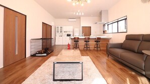 A modern living room with a sofa, a coffee table, and a kitchen in the background. - decopinhouse (Hanamaki)