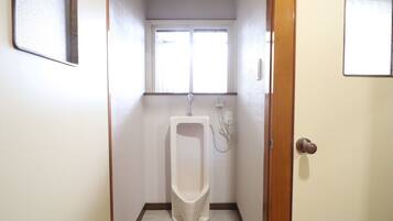 A small, narrow bathroom with a urinal, a window, and a door.
