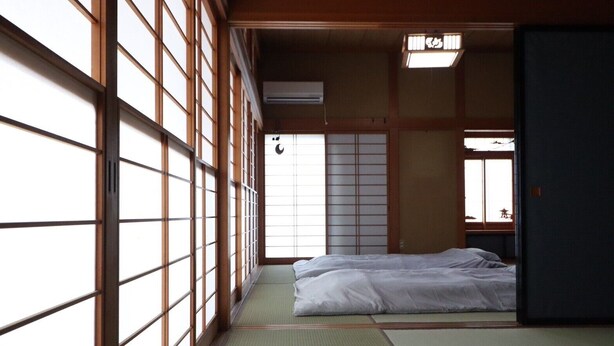 A traditional Japanese room with tatami flooring, a futon bed, sliding doors, and a shoji screen. - decopinhouse (Hanamaki)