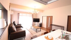 A compact living space with a sofa, TV, and a small kitchen area with a sink and storage. - decopinhouse (Hanamaki)
