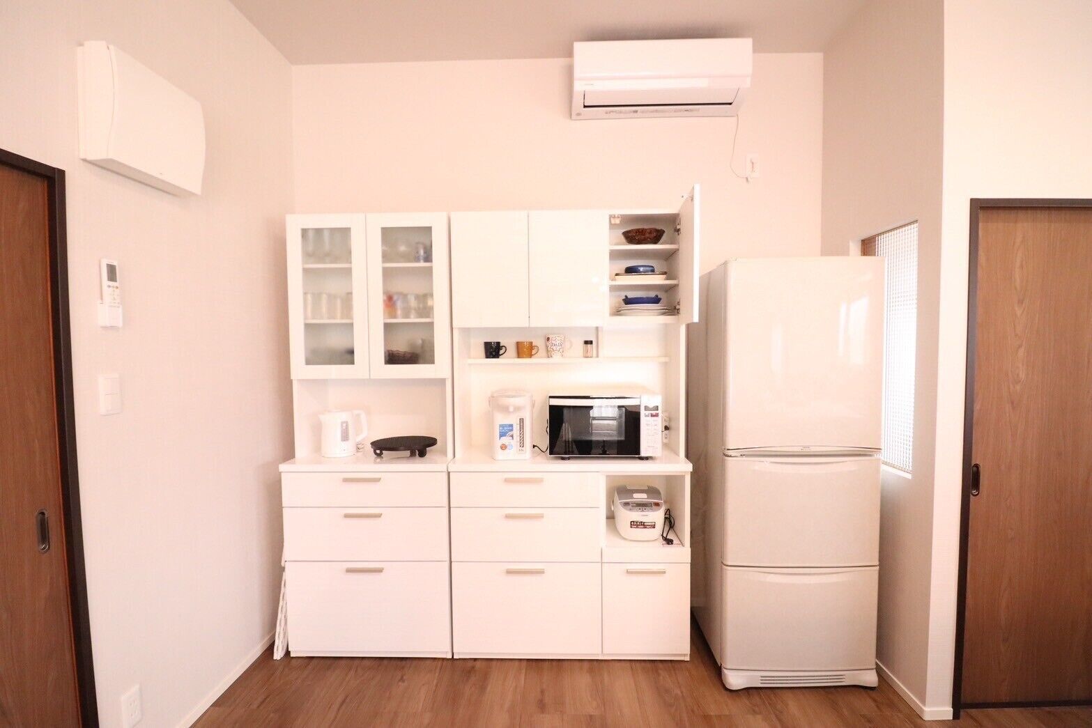 A compact kitchen with white cabinetry, a microwave, a coffee maker, and a refrigerator.