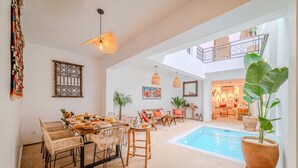 Un vaste espace intérieur doté d’une piscine, de meubles en osier et d’un balcon.