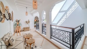 Un intérieur spacieux avec un plafond haut, un balcon doté d’une balustrade en fer forgé et une lucarne.