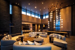 A spacious living area with a large L-shaped sofa set, a coffee table, and a fireplace. There are multiple seating options, including round tables and a bar area in the background. - Corniche Hirafu (Kutchan)