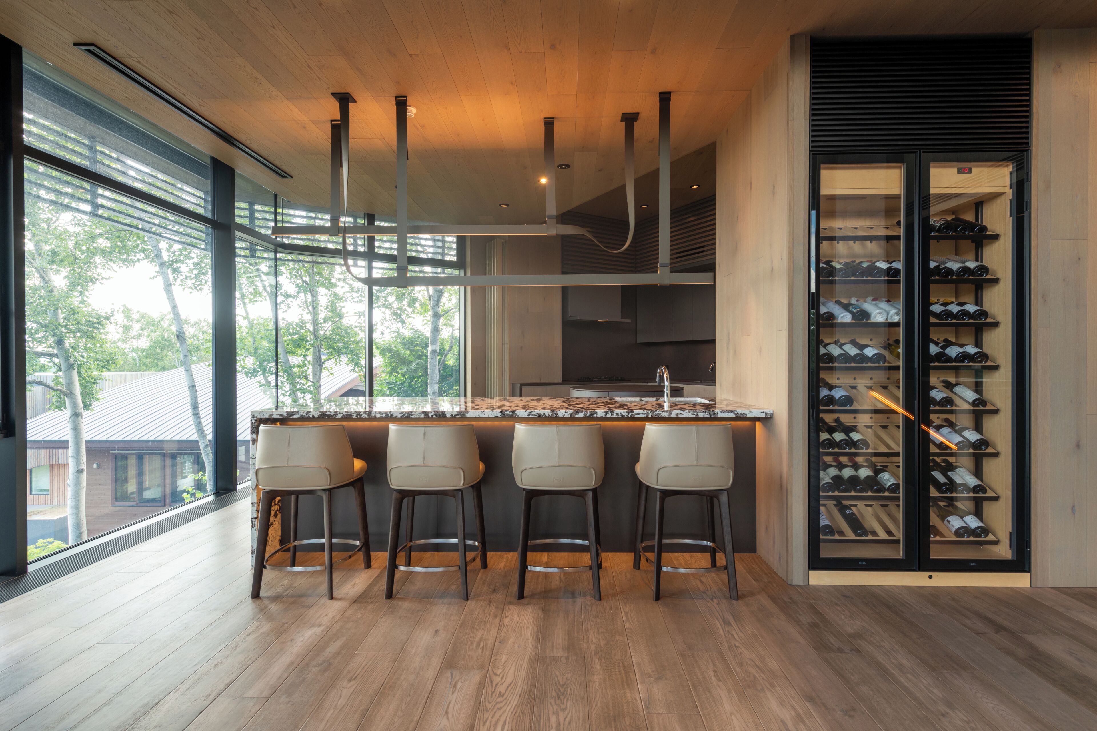 A modern kitchen with a central island, bar stools, and a wine cellar.
