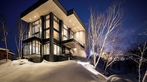 A modern, multi-story building with large windows and a flat roof, surrounded by snow. - Corniche Hirafu (Kutchan)