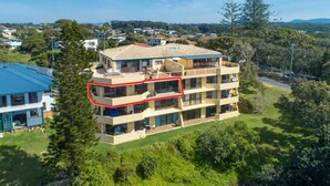 A multi-story building with a flat roof, surrounded by greenery and other buildings. - Ocean Waves - boasting beautiful beach views (Nambucca Heads)