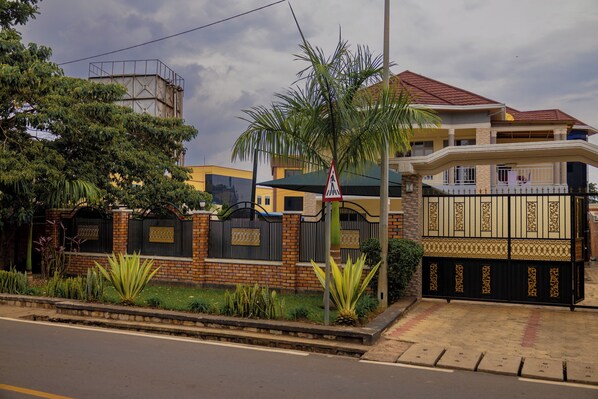 A gated residential area with a brick wall, palm trees, and a pedestrian crossing sign.