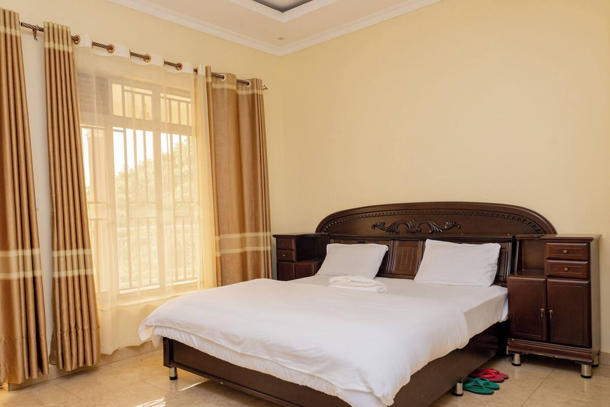 A neatly made bed with white linens, a wooden headboard, and two bedside tables with drawers.