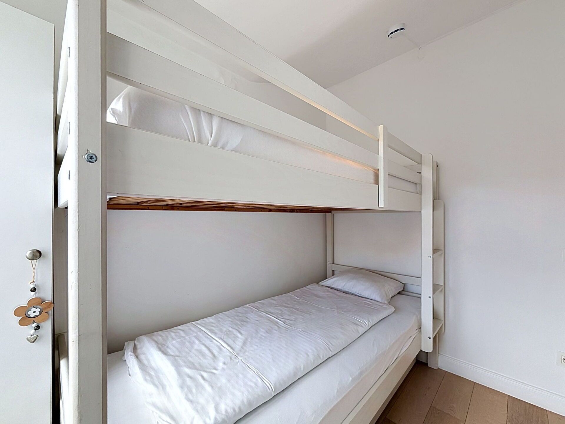 A bunk bed with white bedding and a wooden headboard.