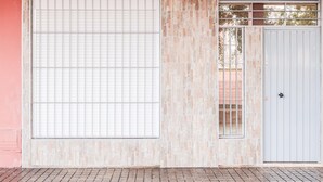Facciata di un edificio con un'ampia porta garage, una porta più piccola e una finestra con inferriata.