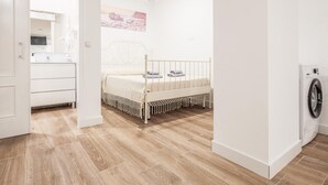 Una camera da letto con un letto, una lavatrice e un bagno visibile attraverso una porta aperta.