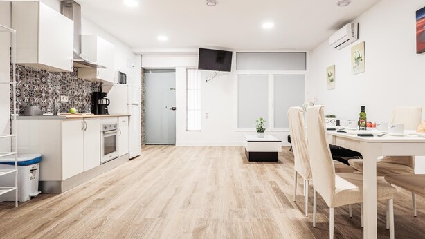 Una cucina moderna con mobili bianchi, uno schienale decorato e un'area pranzo con tavolo e sedie.