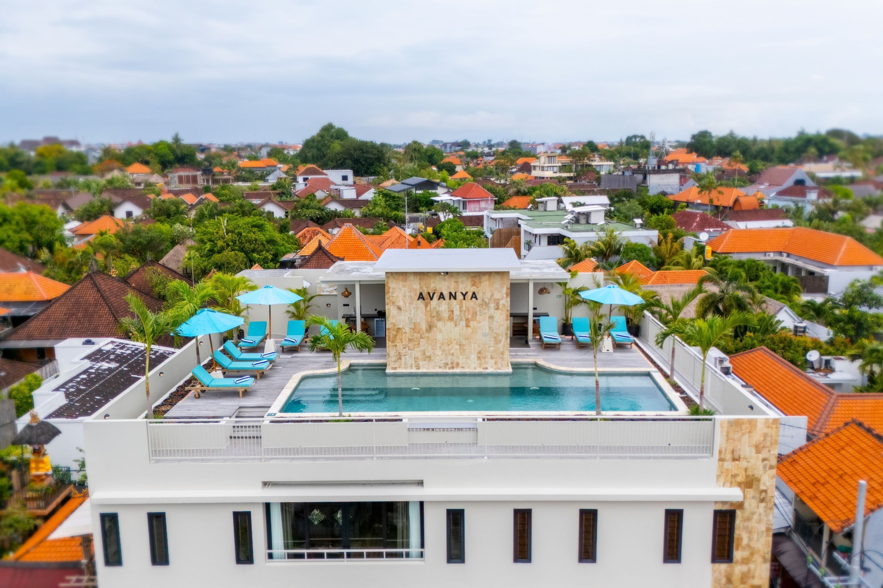 A rooftop pool area with lounge chairs and umbrellas, surrounded by residential buildings.