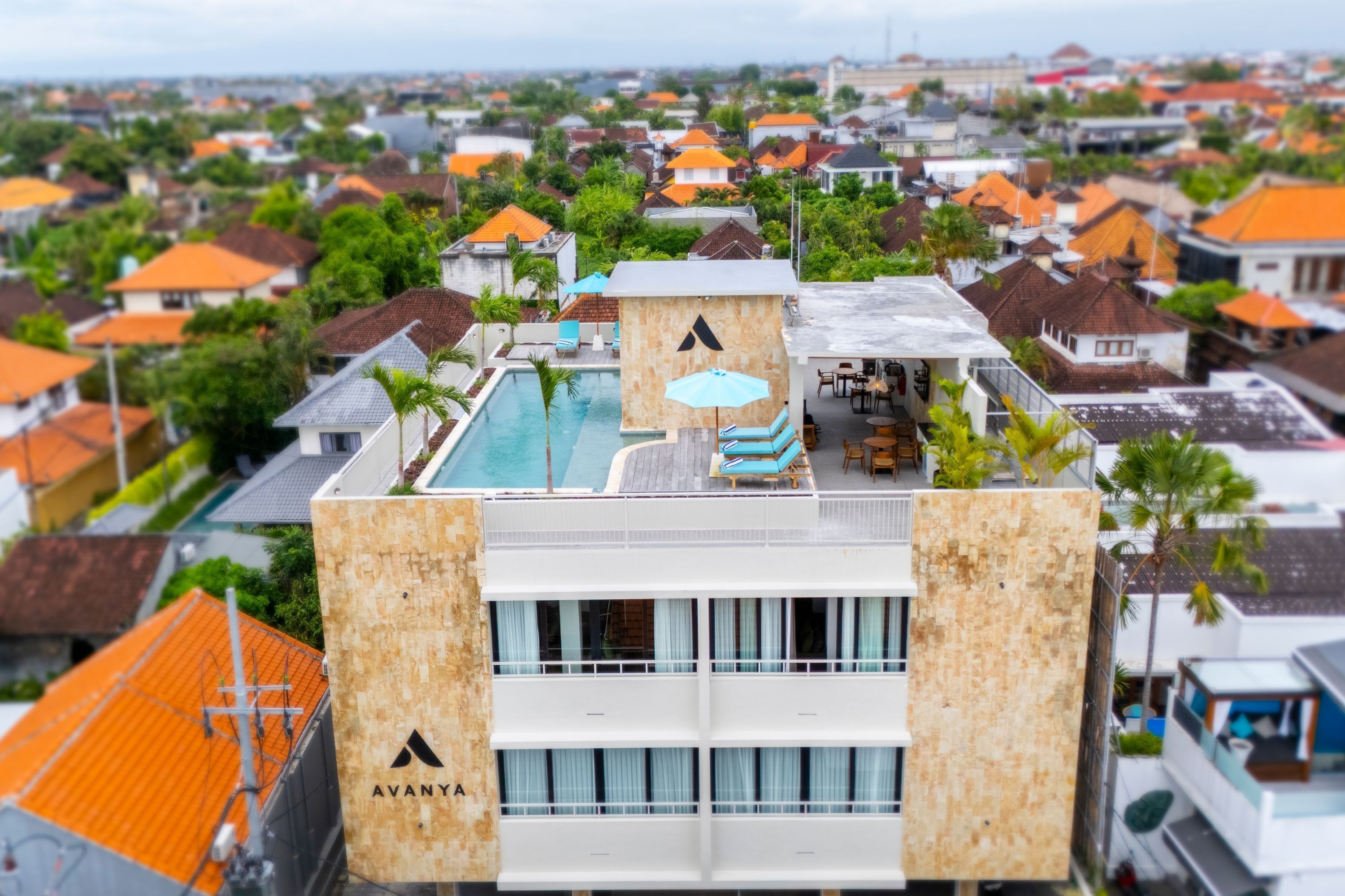 A hotel with a rooftop pool, multiple balconies, and a view of the surrounding neighborhood.