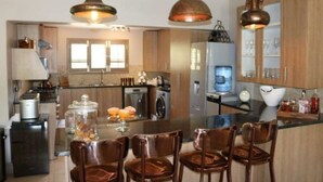 Una cocina moderna con armarios de madera, una isla central con sillas e iluminación colgante de cobre.