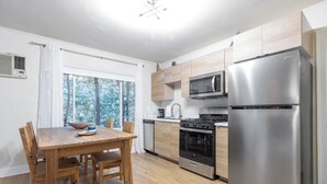 A modern kitchen with wooden cabinets, a stainless steel refrigerator, a microwave, a stove, and a dining table with chairs. - Melrose Village Charmer. Walk to world famous shopping and restaurants. (Los Angeles)