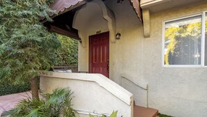 A house with a red door, a concrete front step, and a window with a view of trees. - Melrose Village Charmer. Walk to world famous shopping and restaurants. (Los Angeles)