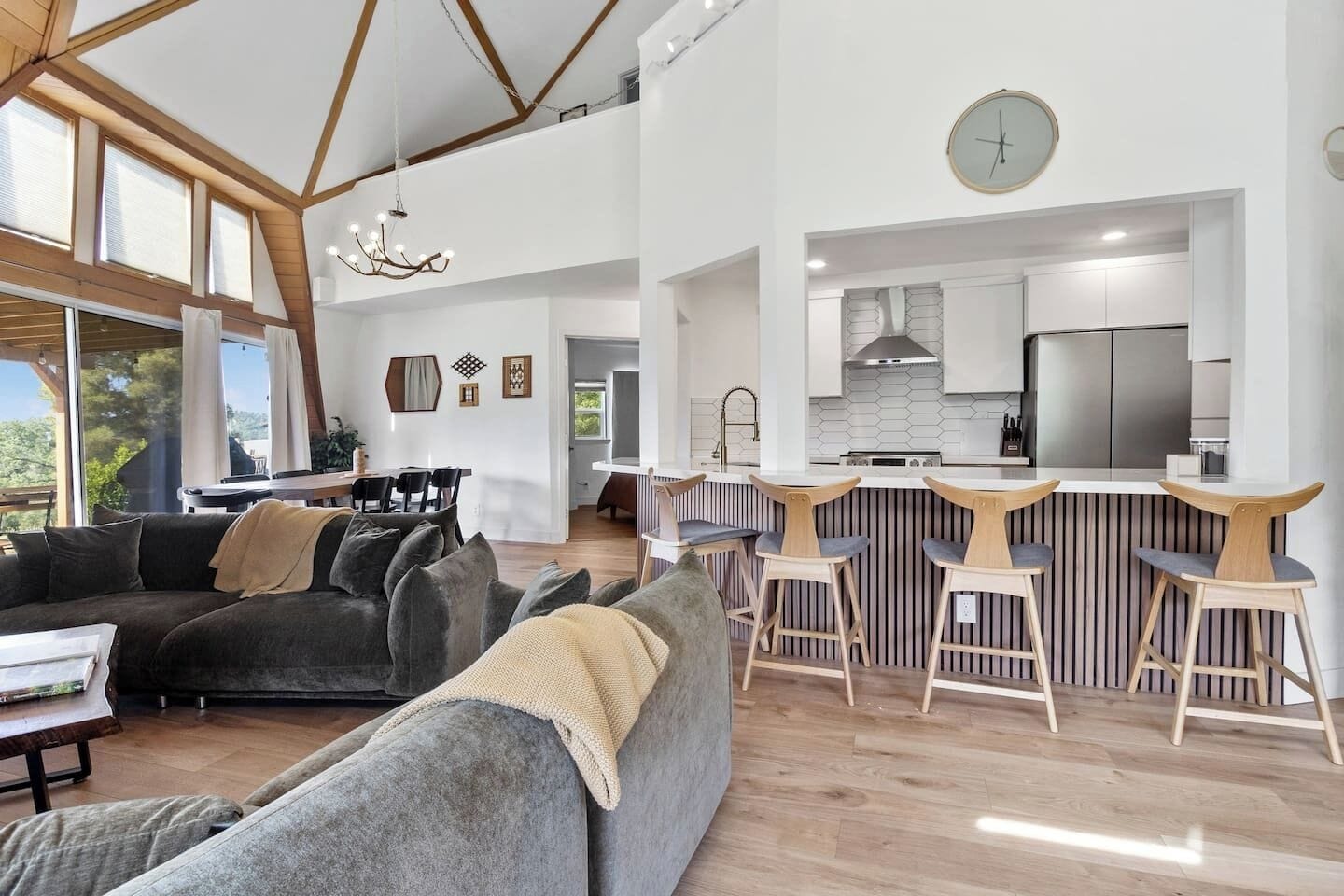 A spacious living area with a large sofa, a dining table, and a kitchen with a bar.