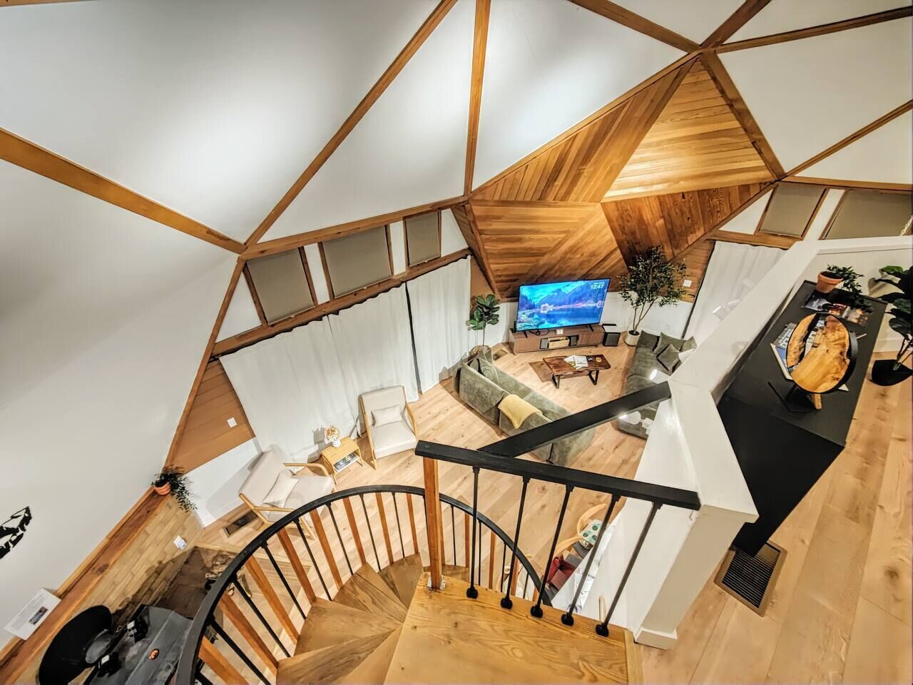 Ein modernes Interieur mit einer Holztreppe, einem Wohnbereich mit Fernseher und einer Küchenzeile.