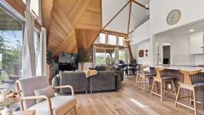 Un interior moderno con techo de madera, un sofá, zona de comedor y cocina.