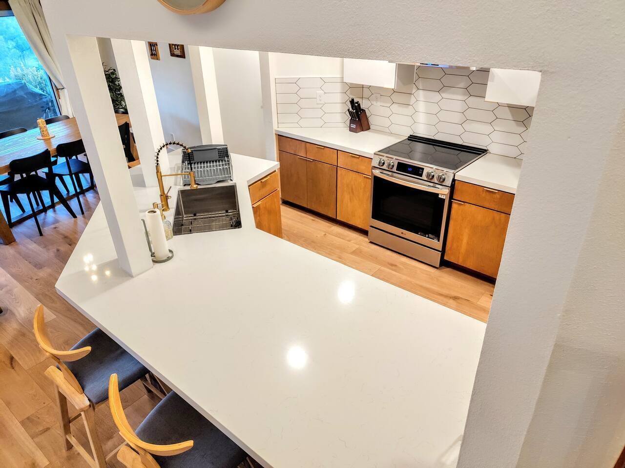 Eine moderne Küche mit weißem Arbeitsplatz, Holzschränken und einem Einbauofen.