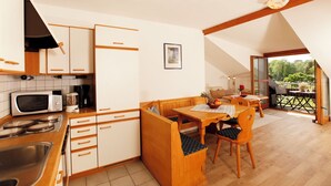 A compact kitchen with white cabinets, a microwave, and a dining area with a wooden table and chairs.