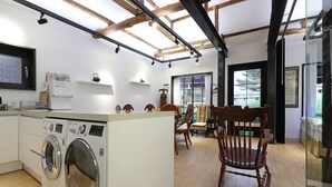 A modern kitchen with a built-in washer, wooden chairs, and a large window.