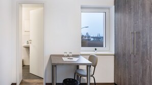 A small room with a table, chair, and a window with a view of a cityscape. - Haus Fuldablick Room '5' with Shared Garden and Wi-Fi (Rotenburg an der Fulda)