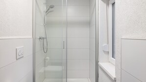A modern bathroom with a glass-enclosed shower, a toilet, and a window. - Haus Fuldablick Room '5' with Shared Garden and Wi-Fi (Rotenburg an der Fulda)