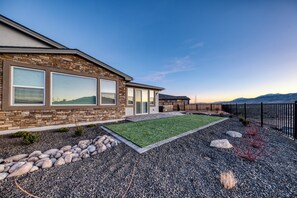 Una casa moderna con fachada de piedra, ventanas amplias y césped cuidado.