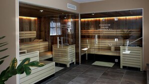 Een sauna met houten banken en glazen wanden, een bordje met een temperatuurindicatie van 90-95°C, en een betegelde vloer.