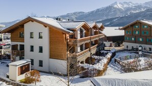 Een modern skigebied met meerlaagsgebouwen, houten balkons en een besneeuwde berg op de achtergrond.