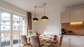 Een moderne keuken met een eethoek, houten vloeren en grote ramen.